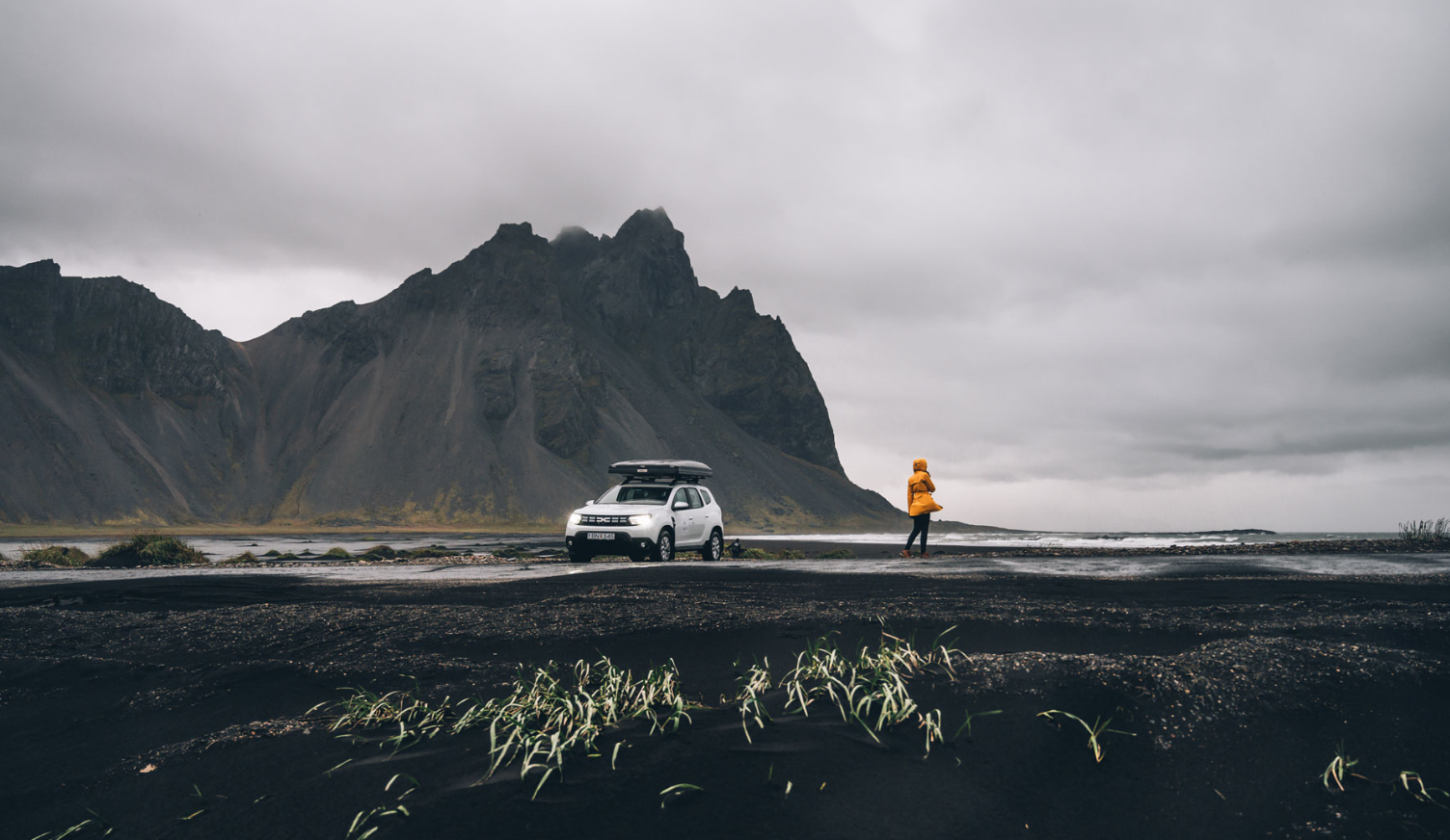 femme se tenant devant un 4x4 sur une plage d'islande