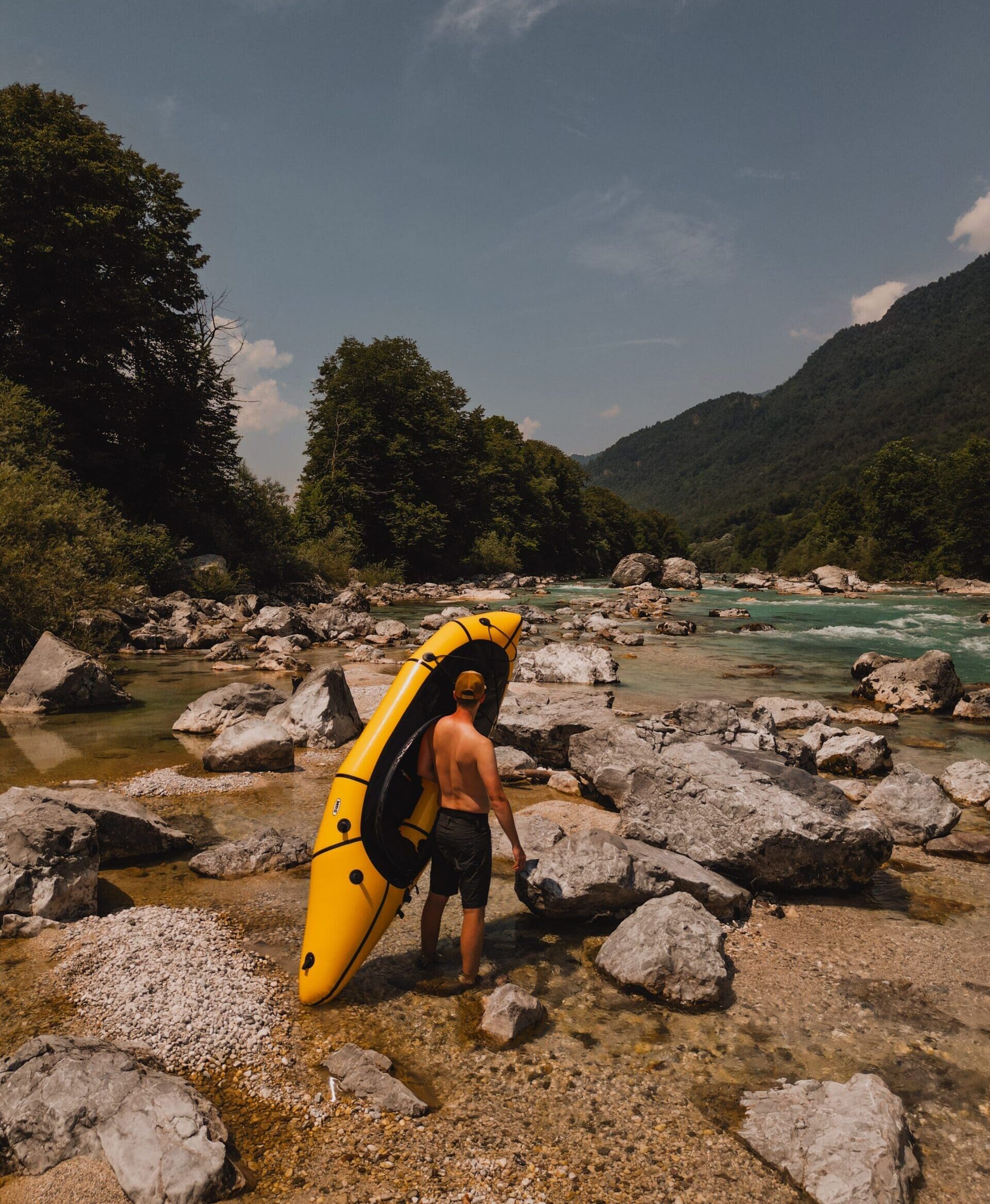 homme portant un packraft sur une rivière en slovénie